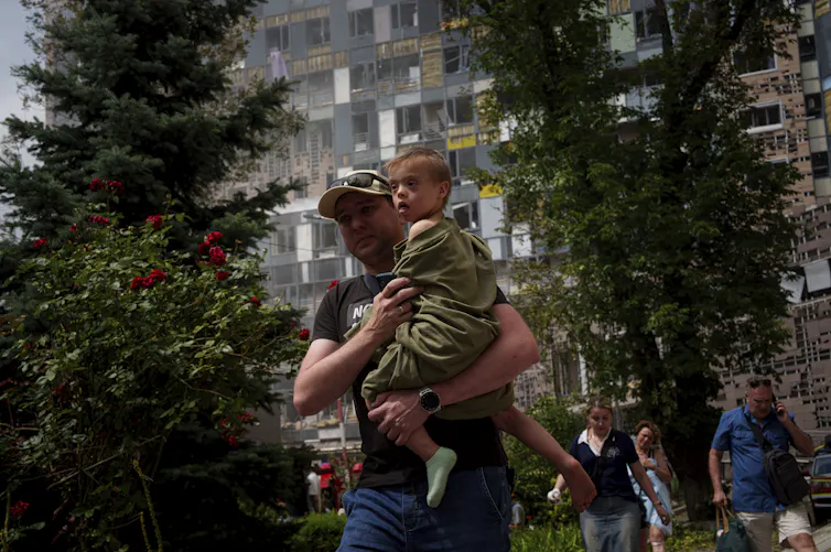A man in a ball cap holds a boy.