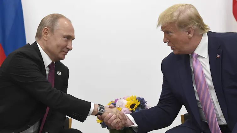 Two men, one balding and the other with greyish blond hair, shake hands as they speak.