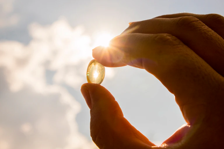Une personne tient un complément alimentaire à base de vitamine D dont l'intérêt n'est pas établi pour les personnes en bonne santé.