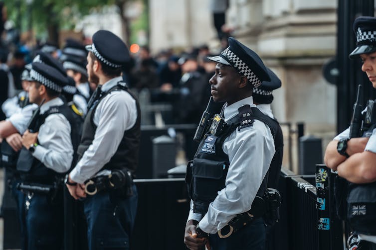 Side view of a black Met officer and several white officers in front of Downing Street