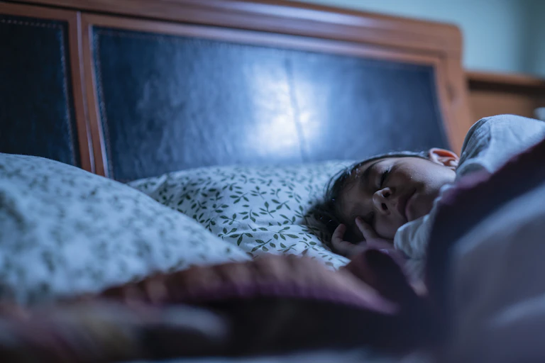 Child sleeping in bed, tucked under blankets