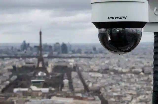 a dark glass semi-sphere hangs from a post in front of a city skyline