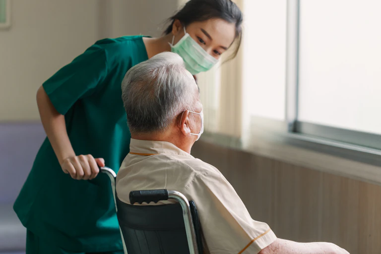 Aged care worker looks at resident in wheelchair