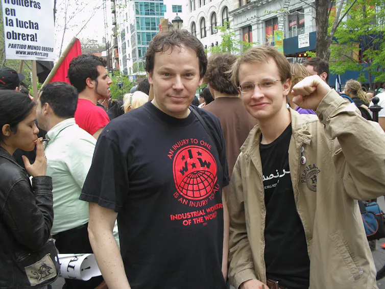 Two men in black t-shirts at a protest.