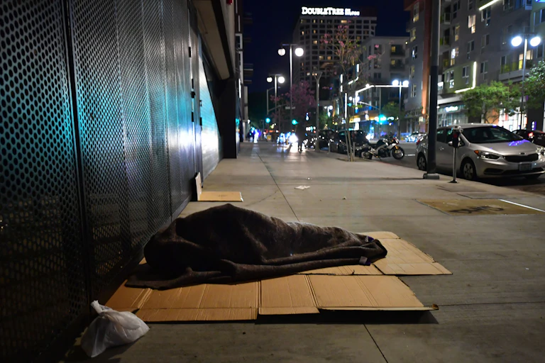 A person sleeps covered with a blanket on cardboard in Los Angeles, California on February 24, 2022.