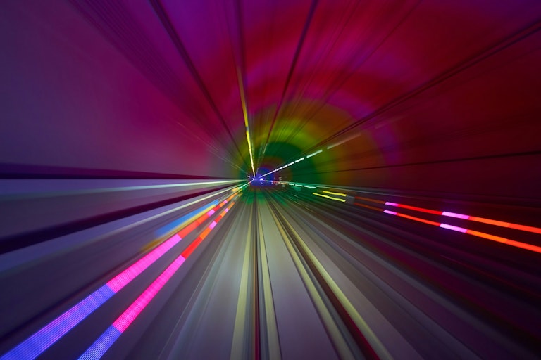 Abstract image of a high-speed tunnel with pink and red lighting.