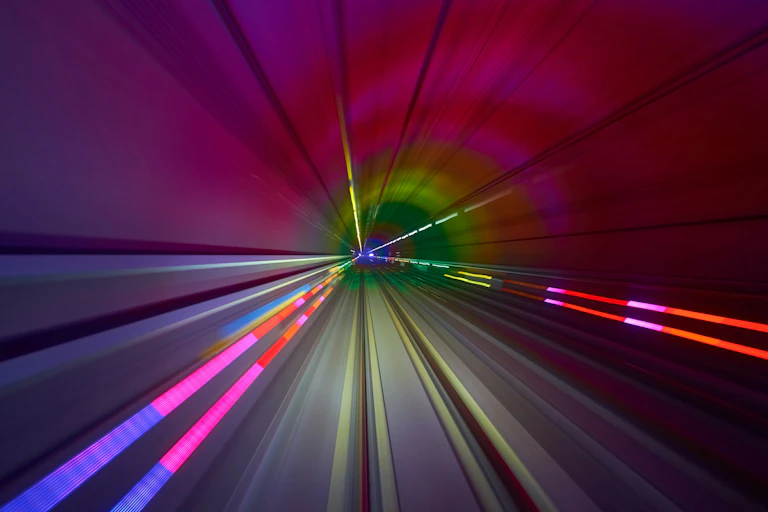 Abstract image of a high-speed tunnel with pink and red lighting.