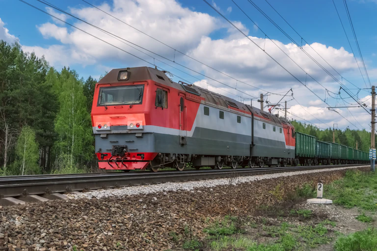 an electric locomotive pulls a freight train along the tracks