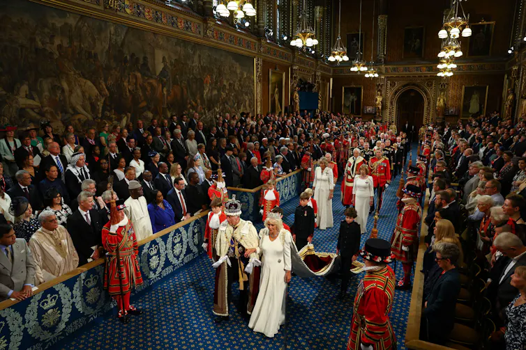 King and Queen walk through middle of crowded chamber