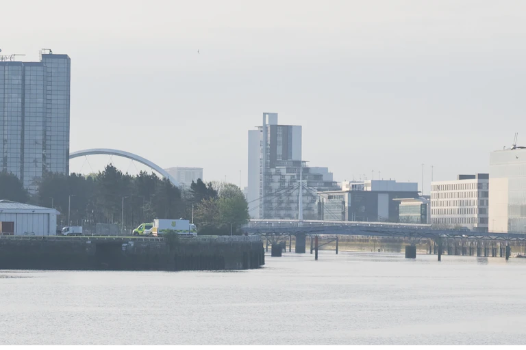 skyline of grey buildings and bridges over wide grey river