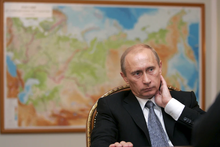 Vladimir Putin sitting in front of a map of Russia
