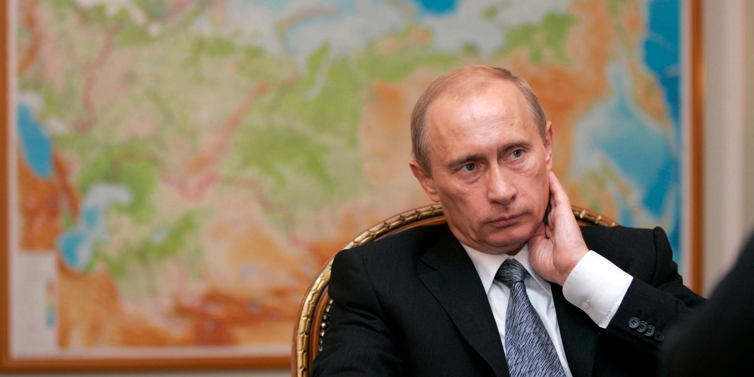 Vladimir Putin sitting in front of a map of Russia