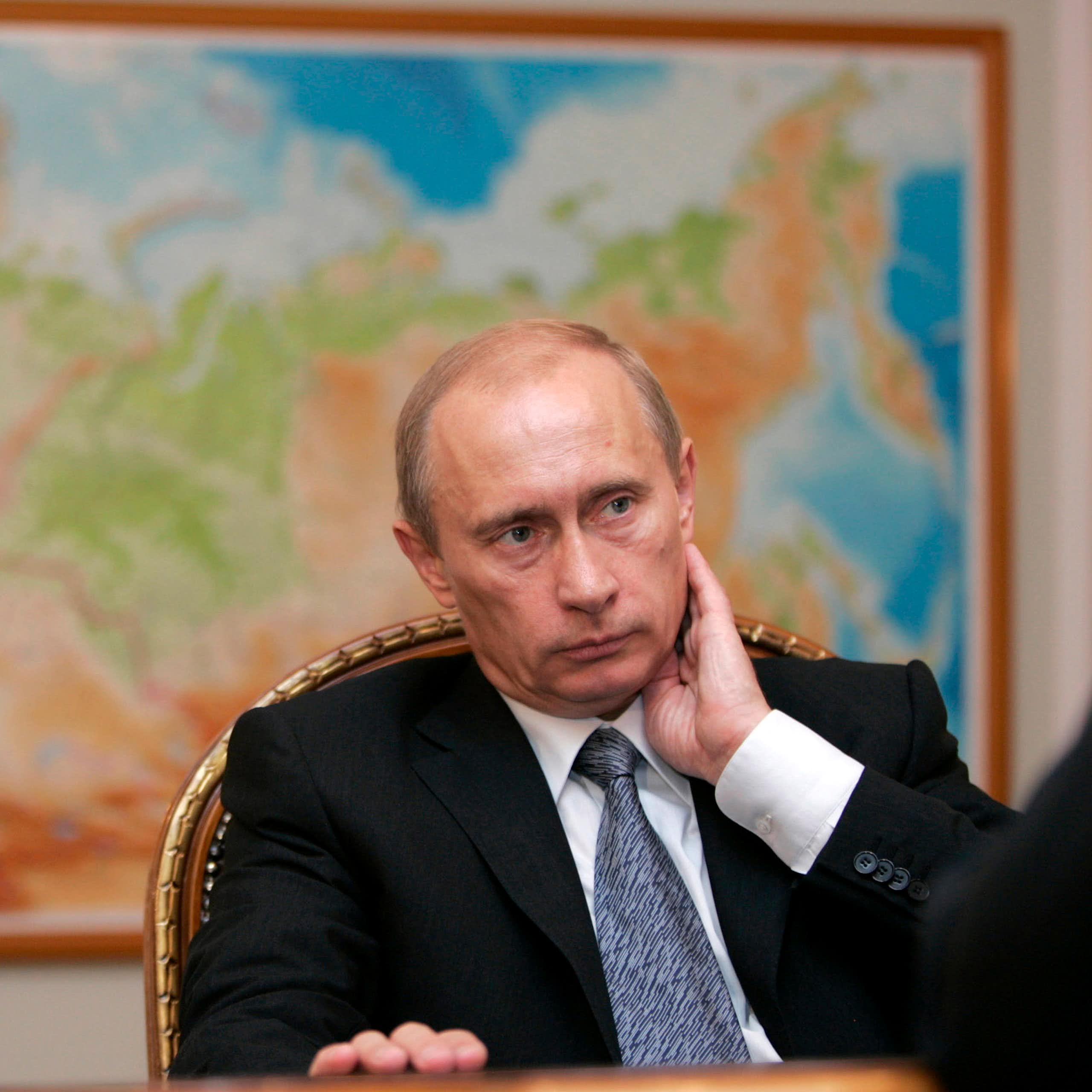 Vladimir Putin sitting in front of a map of Russia