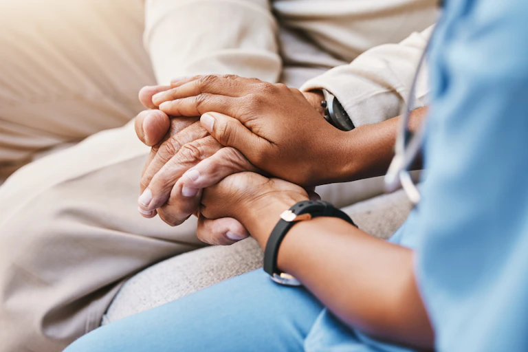 Hands clasped, with one person in medical scrubs.