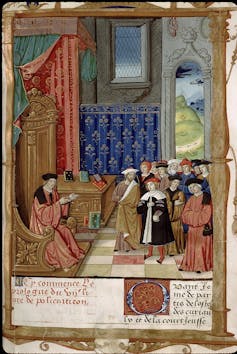 A detailed depiction of a man in a robe and hat sitting on a wooden chair speaking to a group of standing people.
