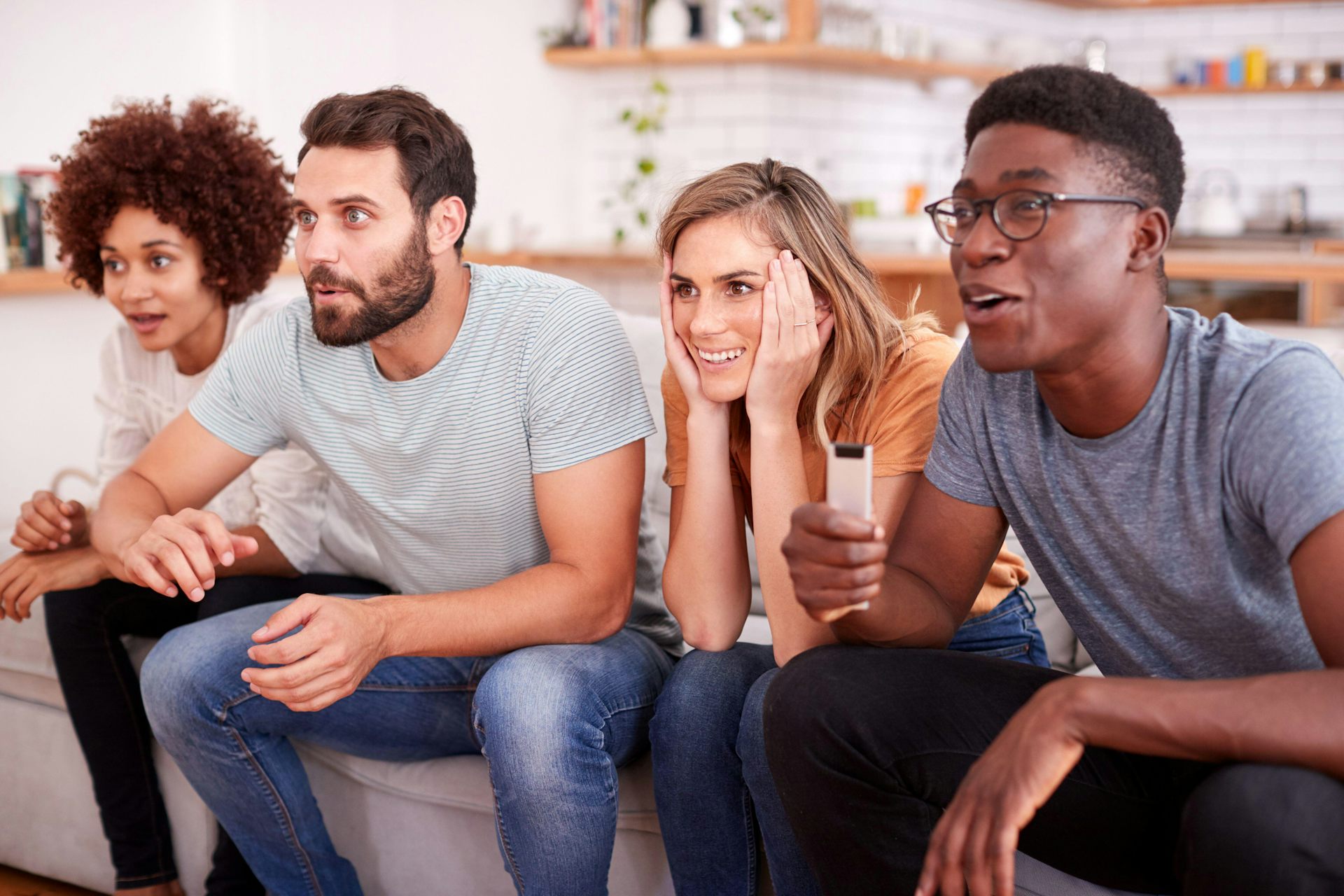 Four people sitting on sofa watching TV. 