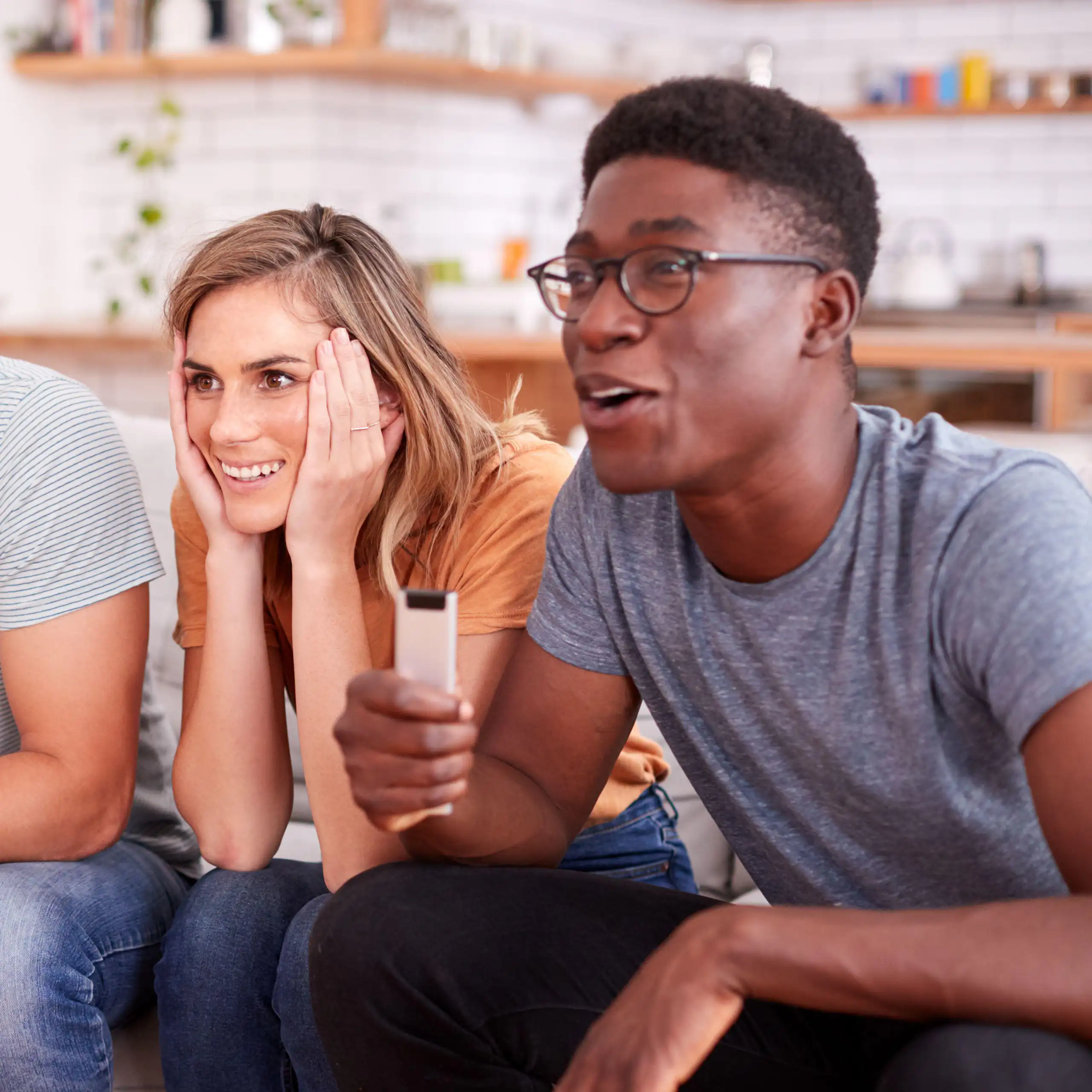 Four people sitting on sofa watching TV.