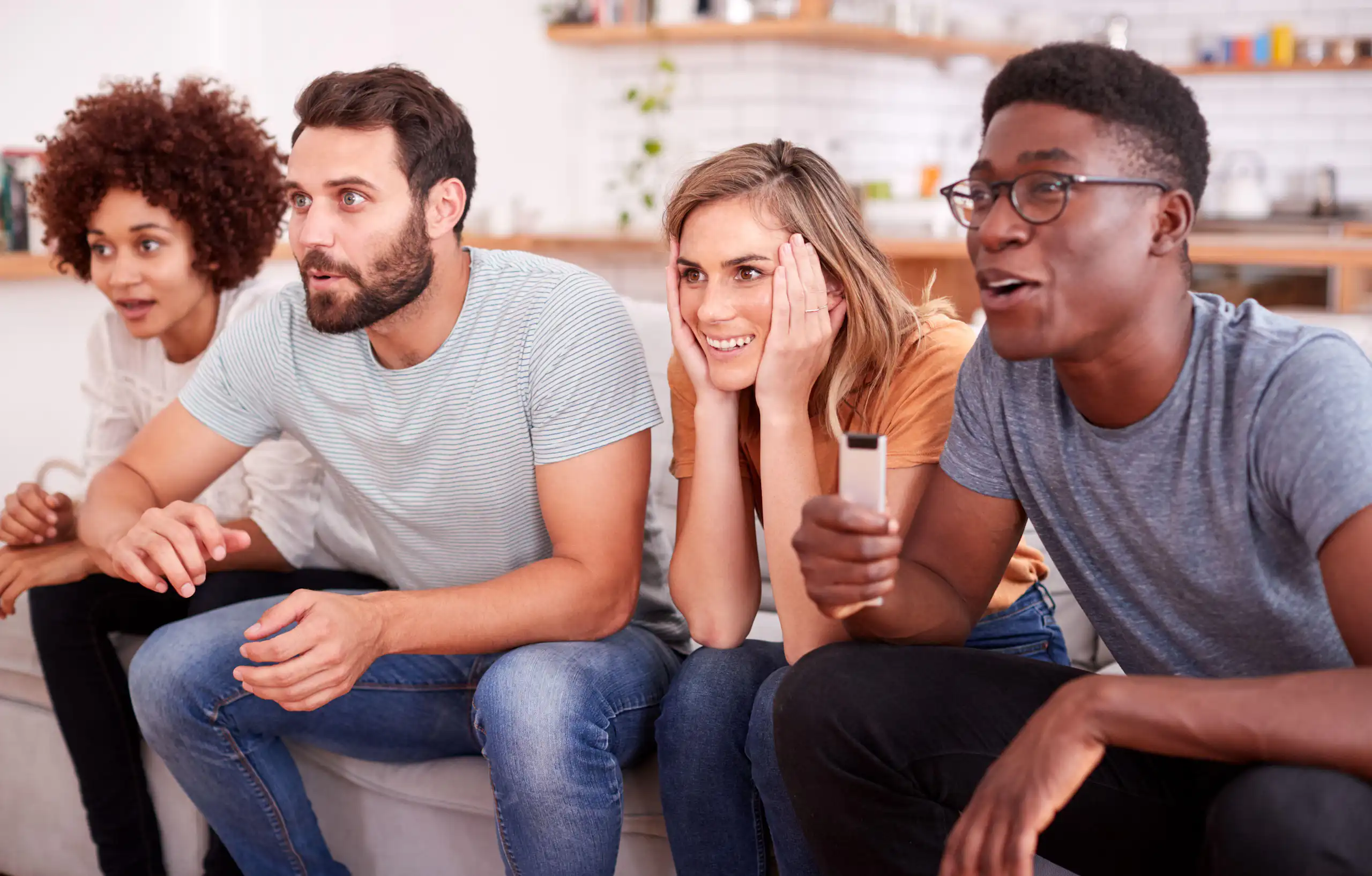 Four people sitting on sofa watching TV.