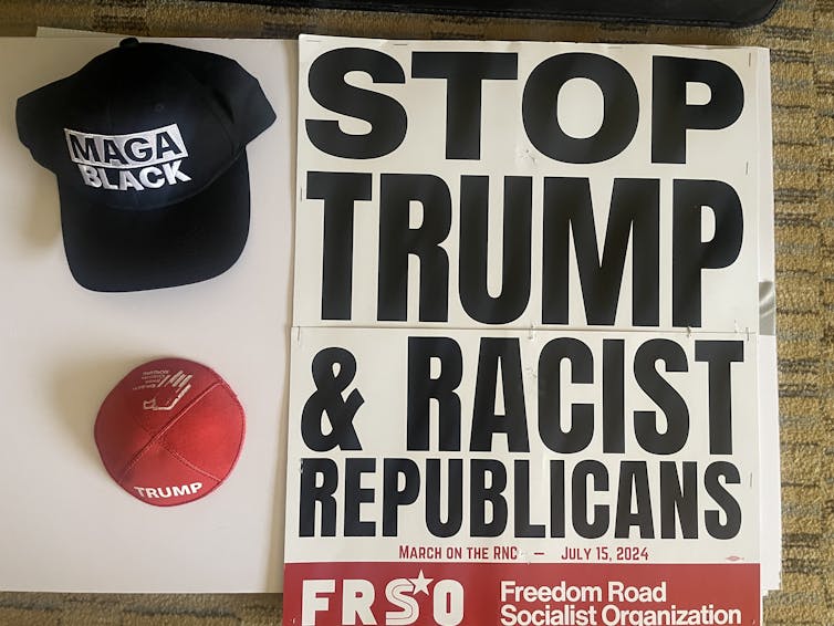 A skullcap, a black hat that says 'MAGA BLACK' on it and a protest poster collected during the 2024 GOP convention.