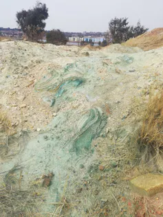 A dry and sandy area with dried green sludge on the ground that contains toxic minerals from abandoned mines