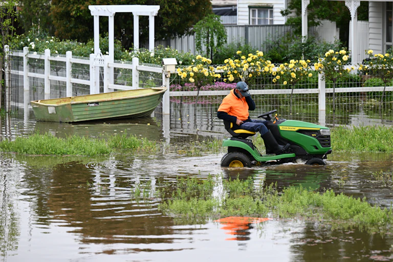man on lawnmower in flood