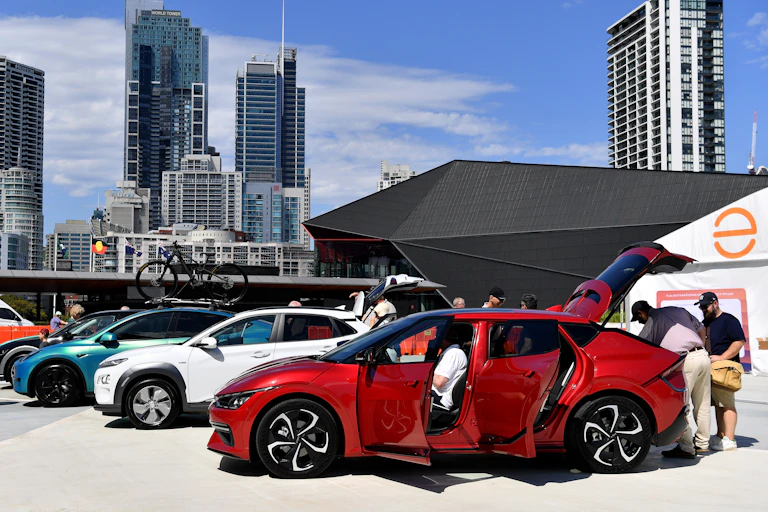 People inspecting a new electric vehicle on display