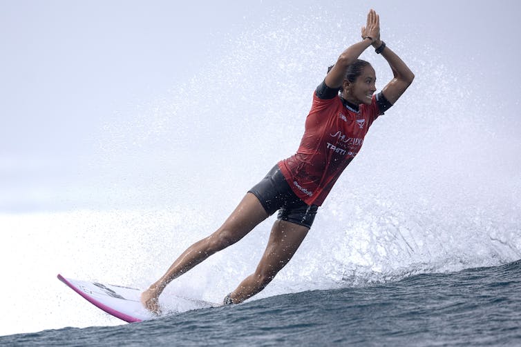 Woman surfer on wave with hands raised