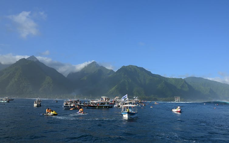 Tahitian coast and mountains viewed from the ocean with small craft in foreground