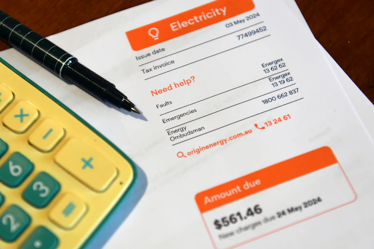 A calculator and pen on top of an electricity bill