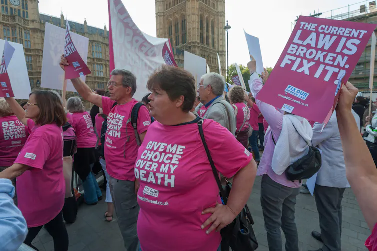 Ativistas com camisetas cor-de-rosa e slogans pedindo a legalização do suicídio assistido do lado de fora do parlamento do Reino Unido, em Westminster