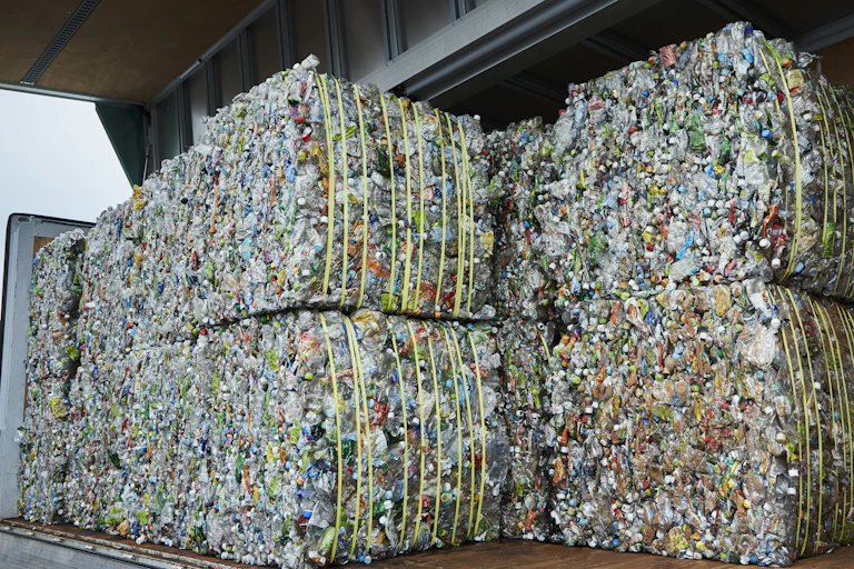 Square pallets of plastic recycling waste sit on a dock at a recycling facility.