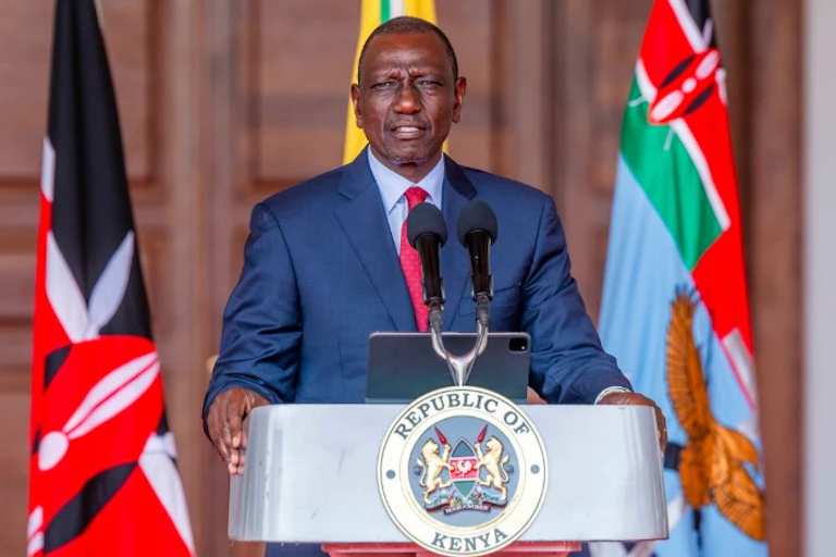 Man in suit and tie standing at a podium marked 'Republic of Kenya'