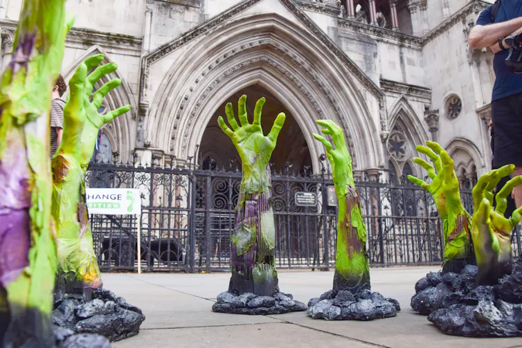 Green zombie hands outside old court building