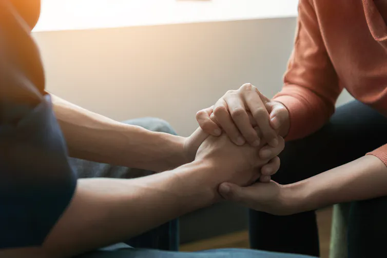 Two people holding hands in a comforting way