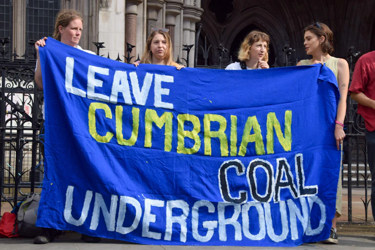 People hold up 'leave cumbrian coal underground' banner