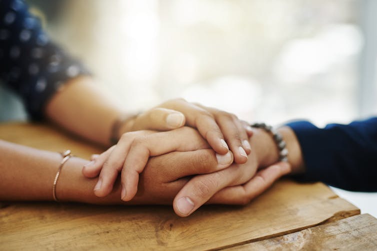 Person wrapping two hands around another person's hand