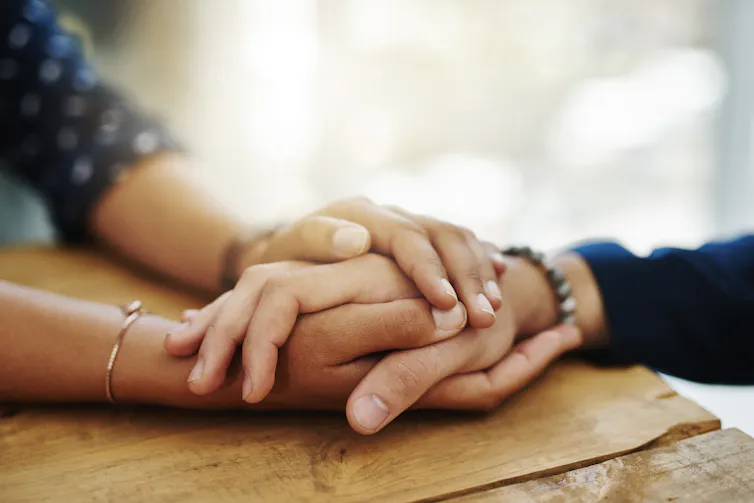 Person wrapping two hands around another person's hand