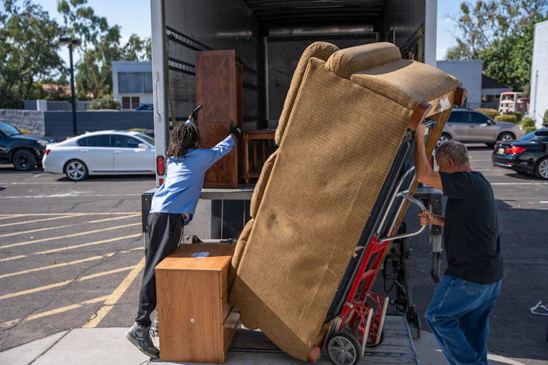 People hauling furniture from a truck.
