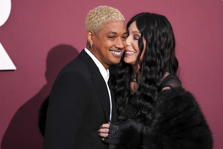 An older white woman and younger black man pose for a photo together smiling