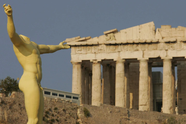 A replica of an ancient statue is seen in front of the Acropolis Parthenon in Greece