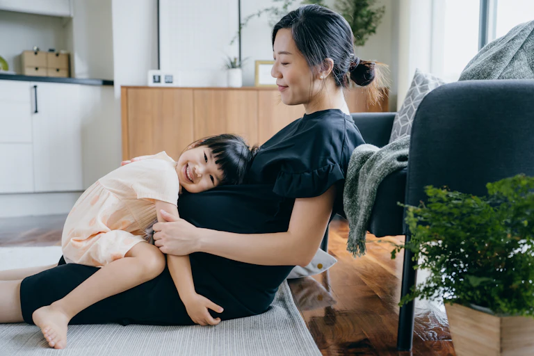 Asian girl embracing her mother's pregnant belly