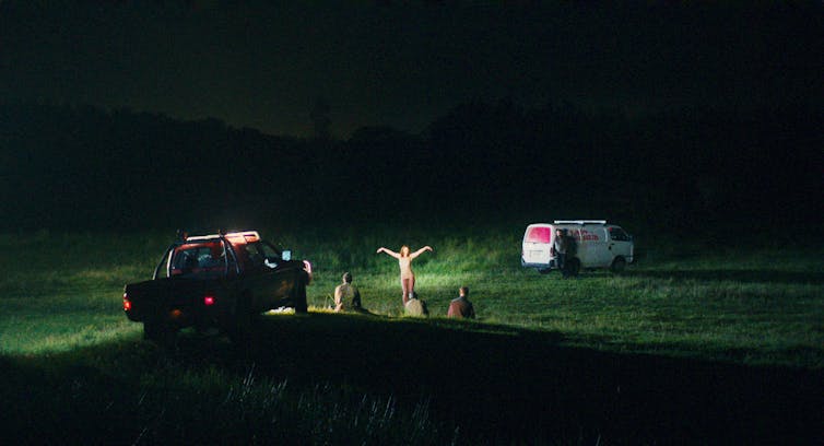 A car and people in a field.