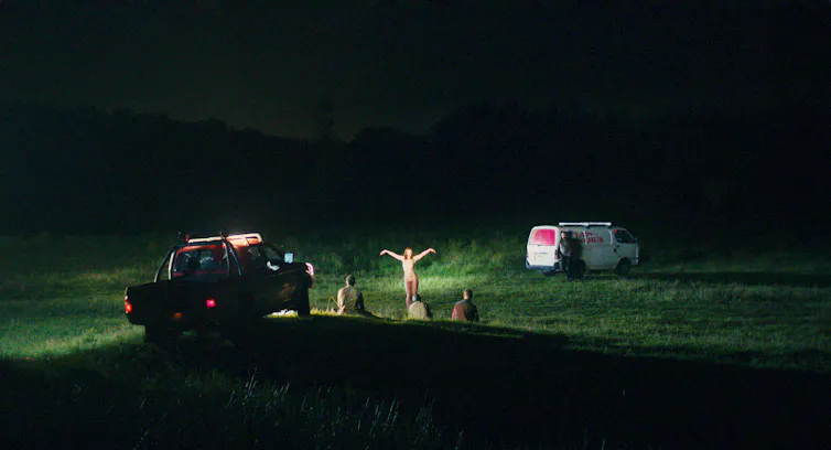 A car and people in a field.