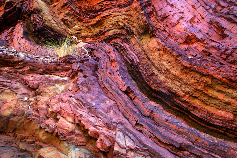Close-up of layered blue orange and purple rock formation.