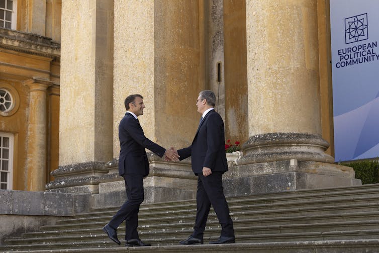 Macron and Starmer shaking hands on the steps of Blenheim Palace