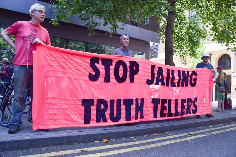 protesters with 'stop jailing truth tellers' banner