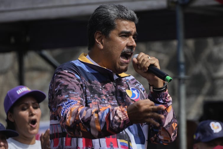 A man holding a microphone speaks to a crowd