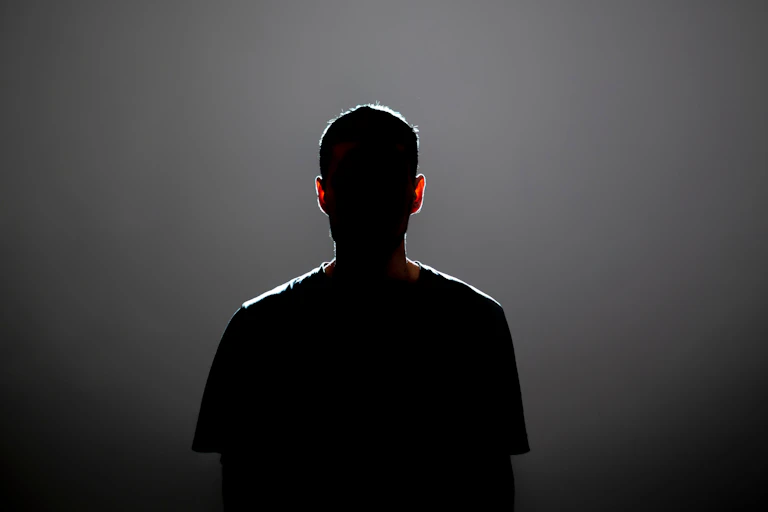 The backlit silhouette of a young man