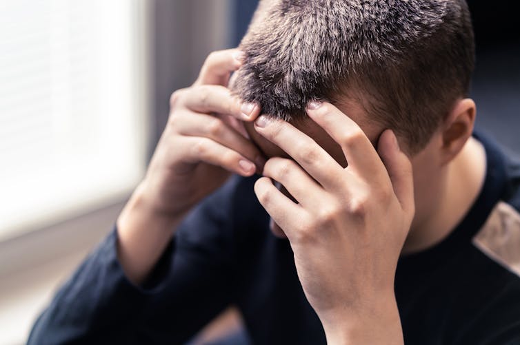 A man holds his head into his hands