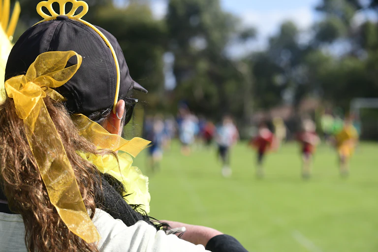 Back of the head of a girl adorned in yellow for sports day.